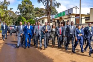 Stakeholders at the summit,October 7 - Sacco Trend Magazine Group of business professionals walking together on a dirt road outside a pavilion, all in formal suits and smart attire.