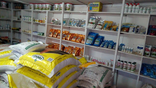 Inside a store with white shelves stocked with groceries; large yellow-and-white bags on the floor in front.