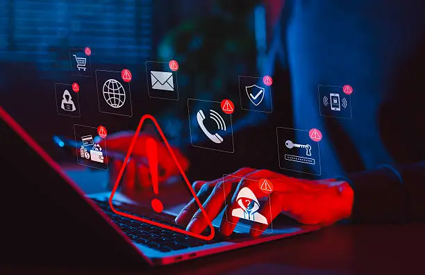 istockphoto-2222587920-612x612 - Sacco Trend Magazine Laptop with red warning symbol and floating security icons, signaling a cybersecurity alert or breach.