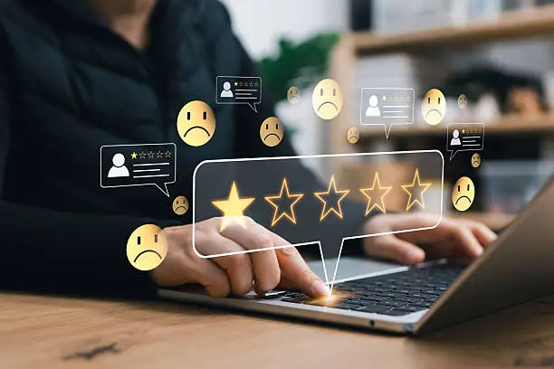 Person typing on a laptop with glowing five-star rating icons and chat bubbles representing online reviews and feedback.