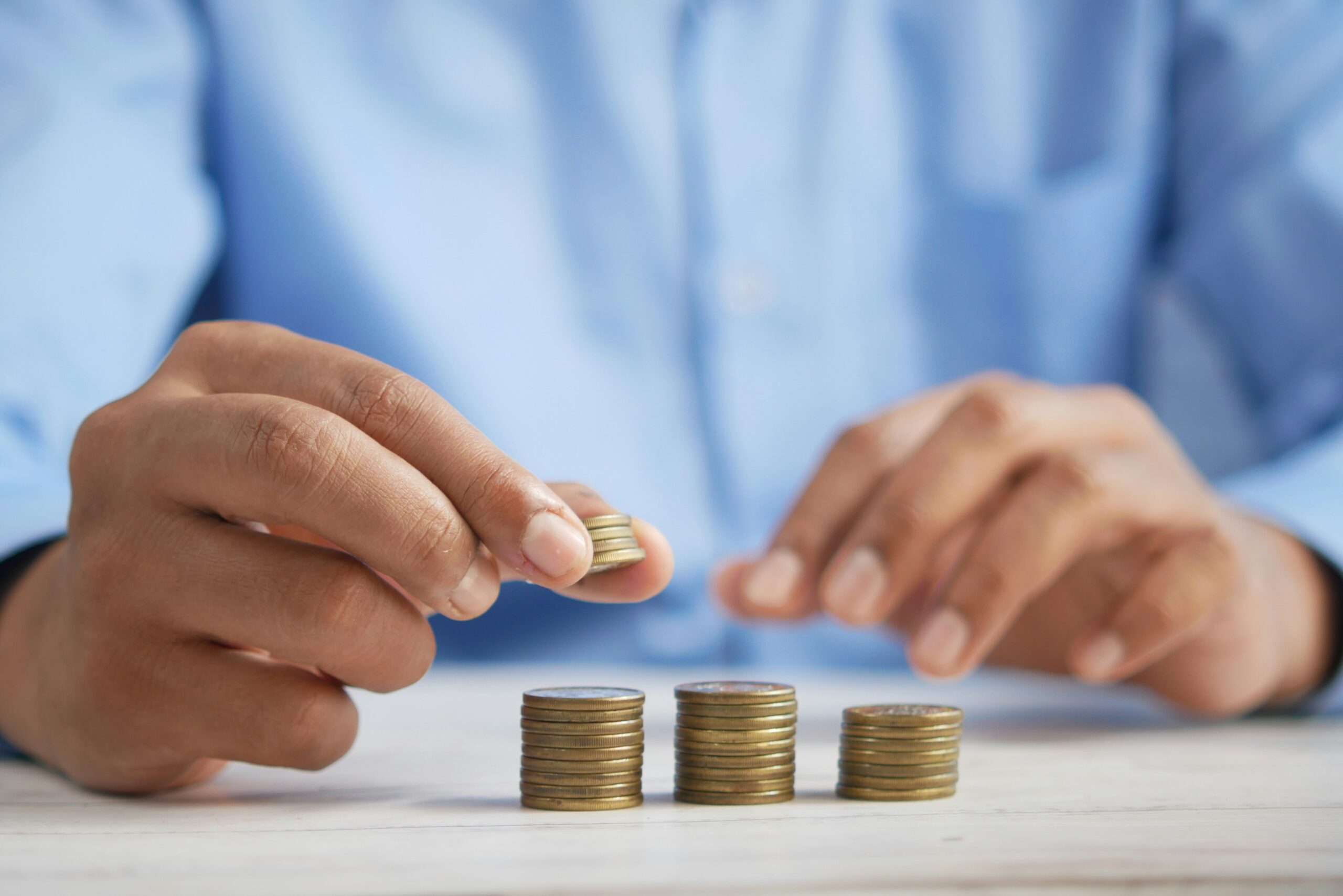 Close-up of hands stacking coins into small towers on a table surface